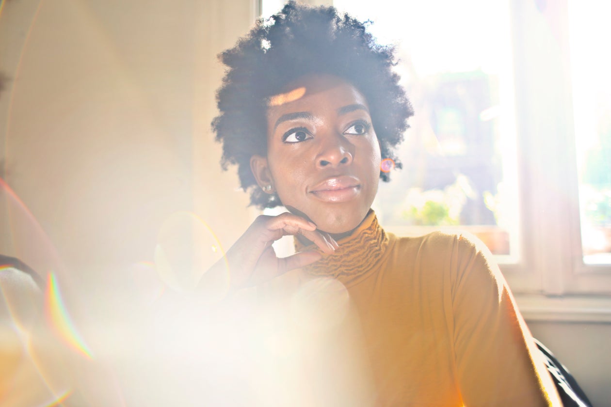 A Black woman in soft golden morning light, pausing to reflect